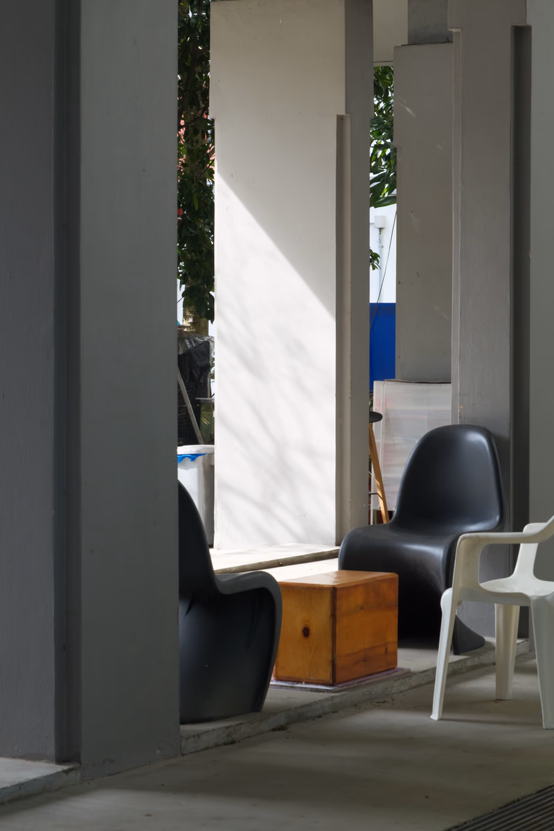 A modern outdoor seating area with black and white chairs and a wooden box.